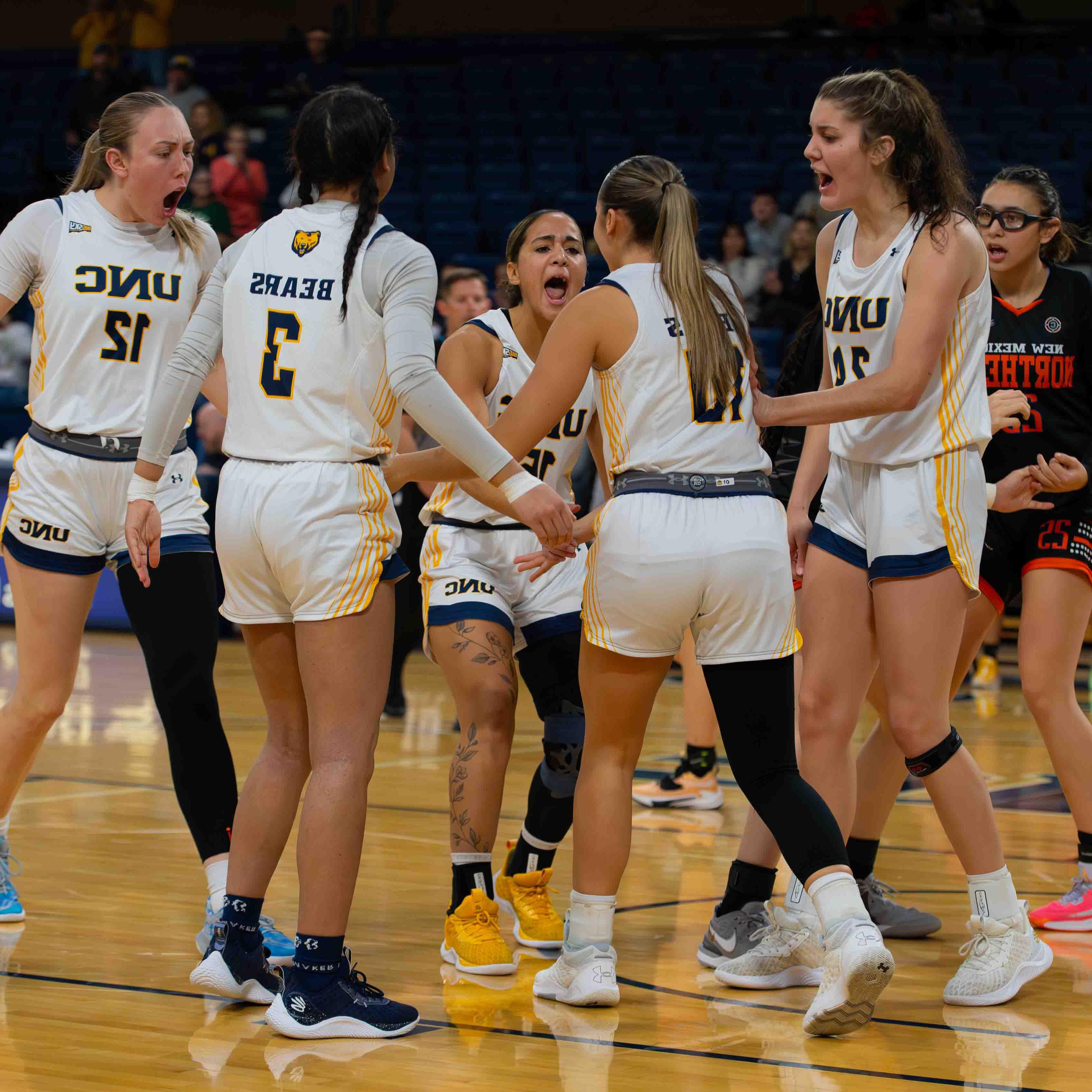 Women's basketball players celebrate on the court during a game.